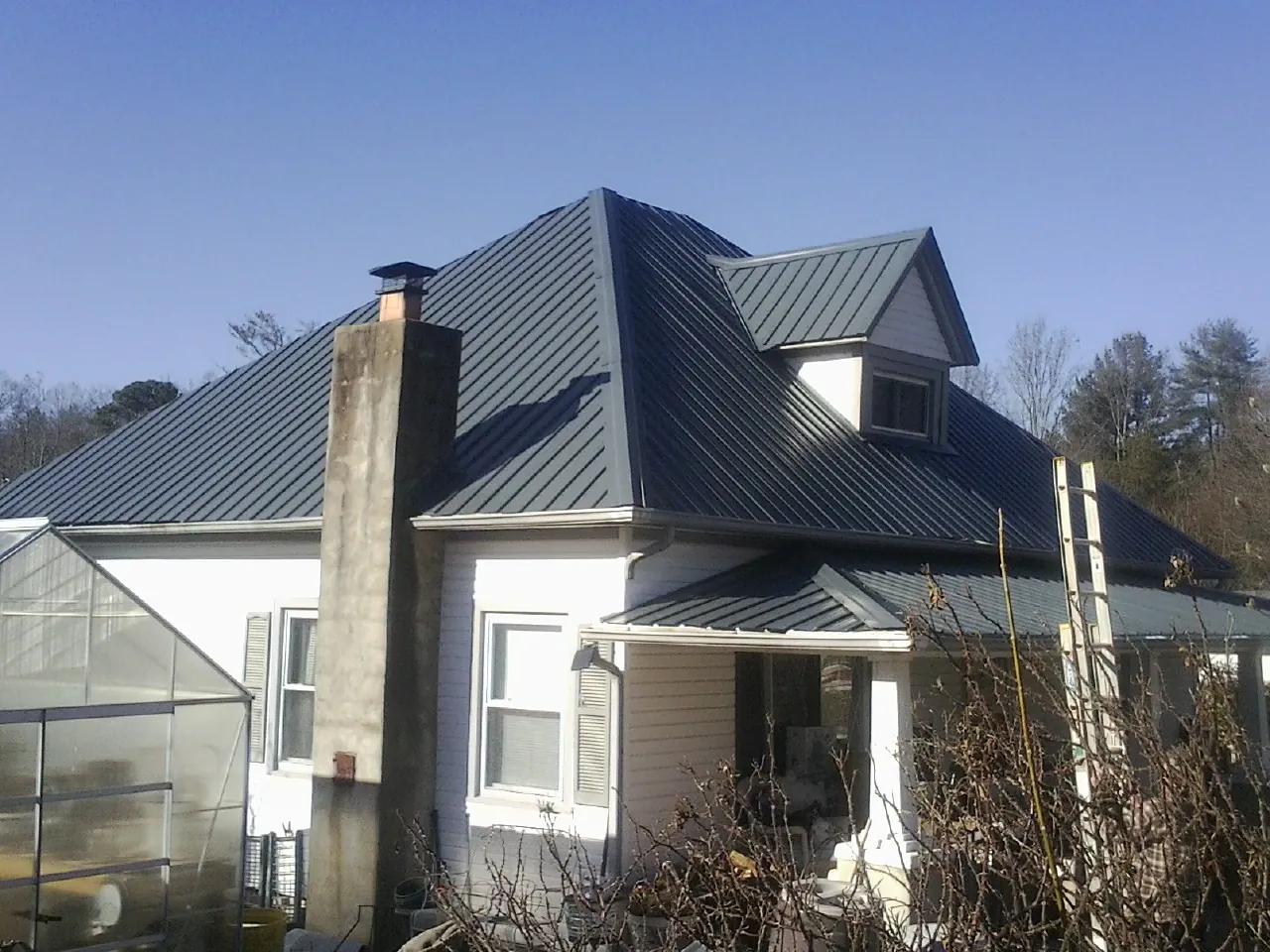Dark blue standing seam metal roof on a white farmhouse with dormer — Slate & Tile Roof Repair by Roofing Brothers in Sun River