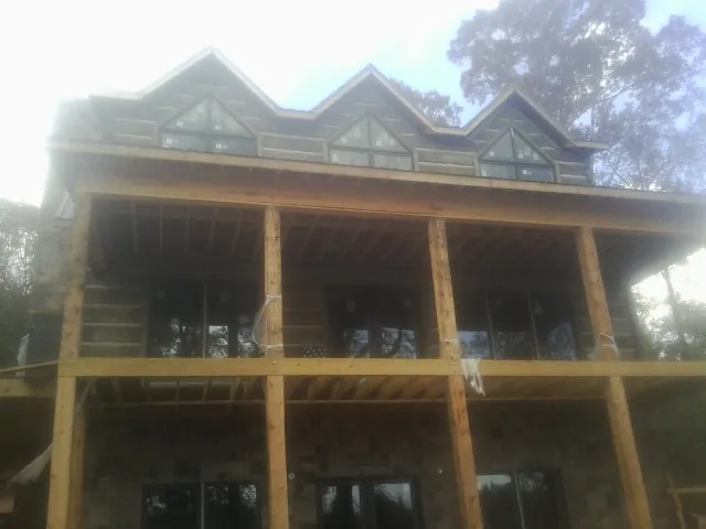Dormers and porch framing on a large log home under construction — Roof Coating work by our crew in Sun River