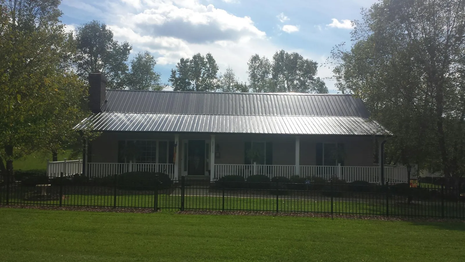 Gray metal roof on a brick ranch with a full width front porch — Gutter Guard Installation work by our crew in Sun River