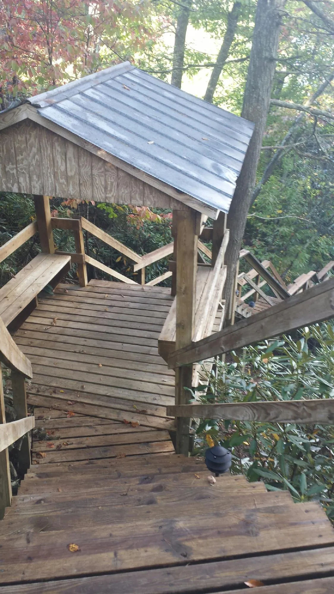 Metal roofed shelter over wooden steps on a wooded walkway — Skylight Repair & Installation work by our crew in Sun River