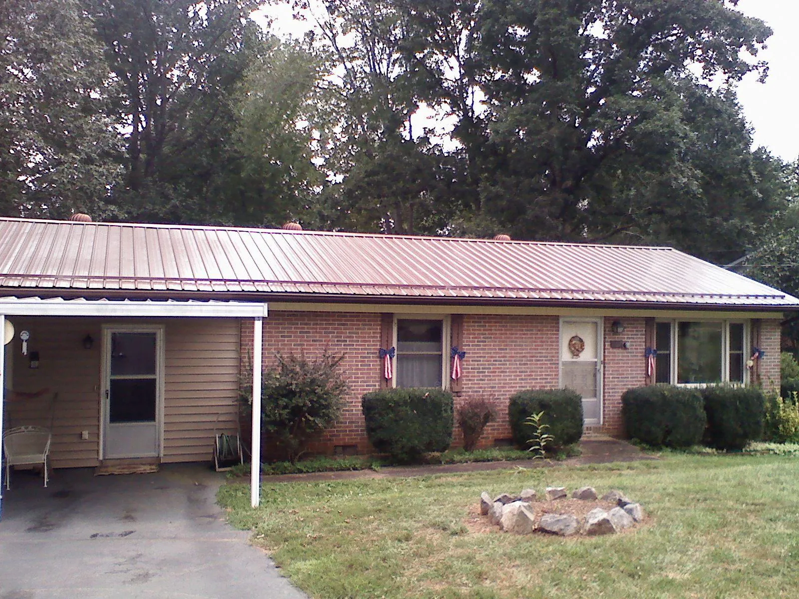 Bronze metal roof and carport on a brick ranch home — Roof Repair work by our crew in Sun River