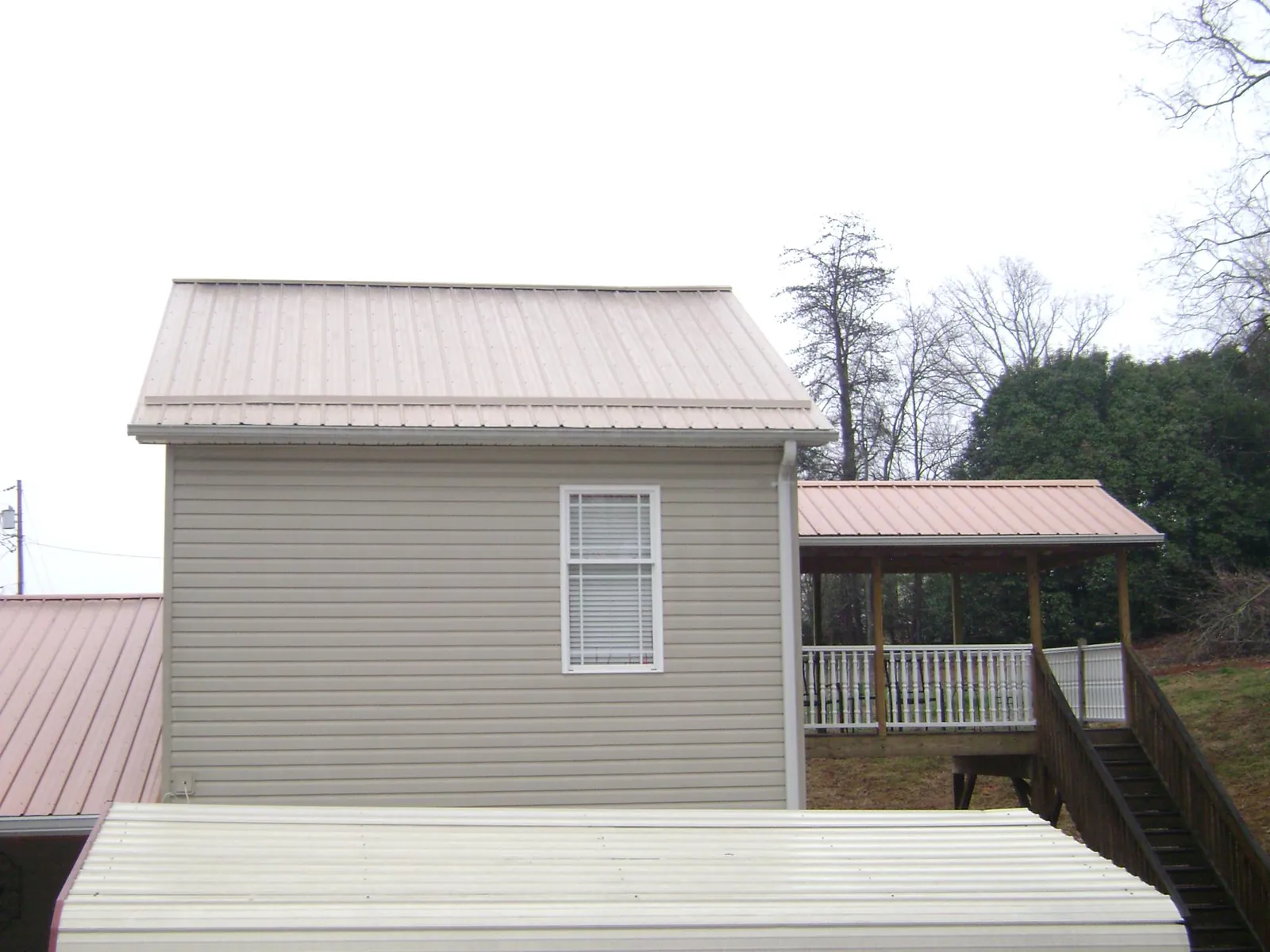 Tan metal roofs on a two story addition and attached porch, from a Roof Replacement job in Sun River