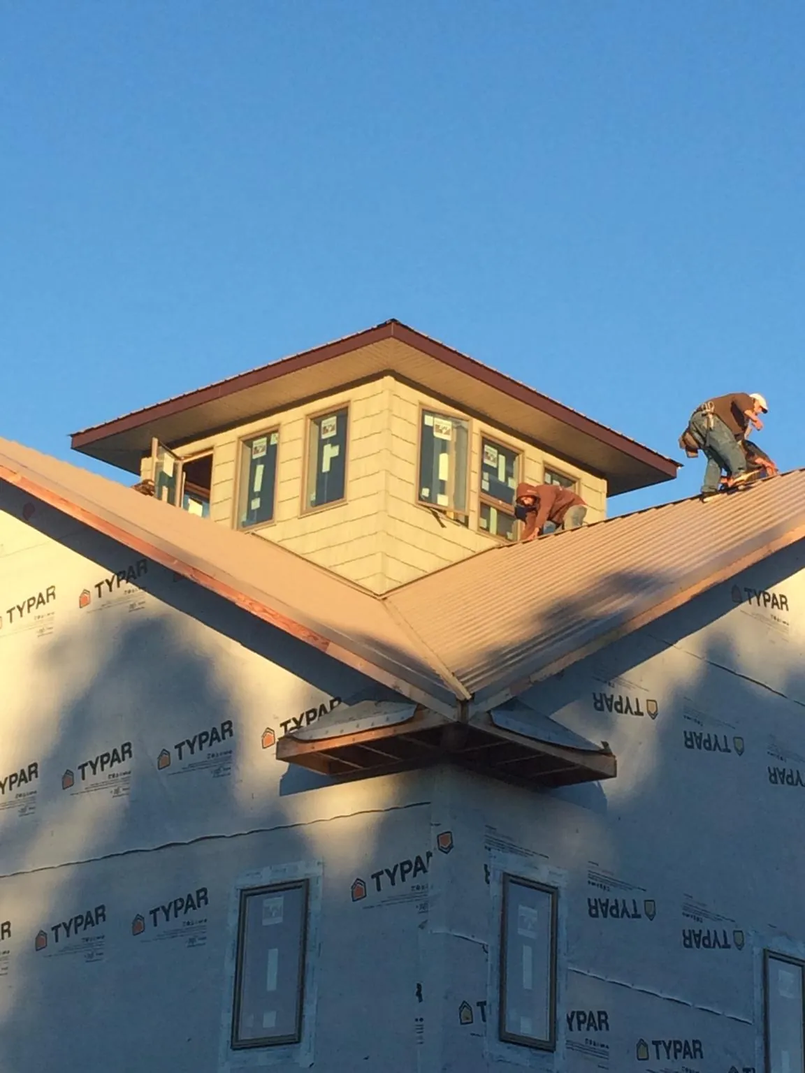 Roofers working around a rooftop cupola on a new metal roof at sunset — Roof Waterproofing in Sun River by Roofing Brothers